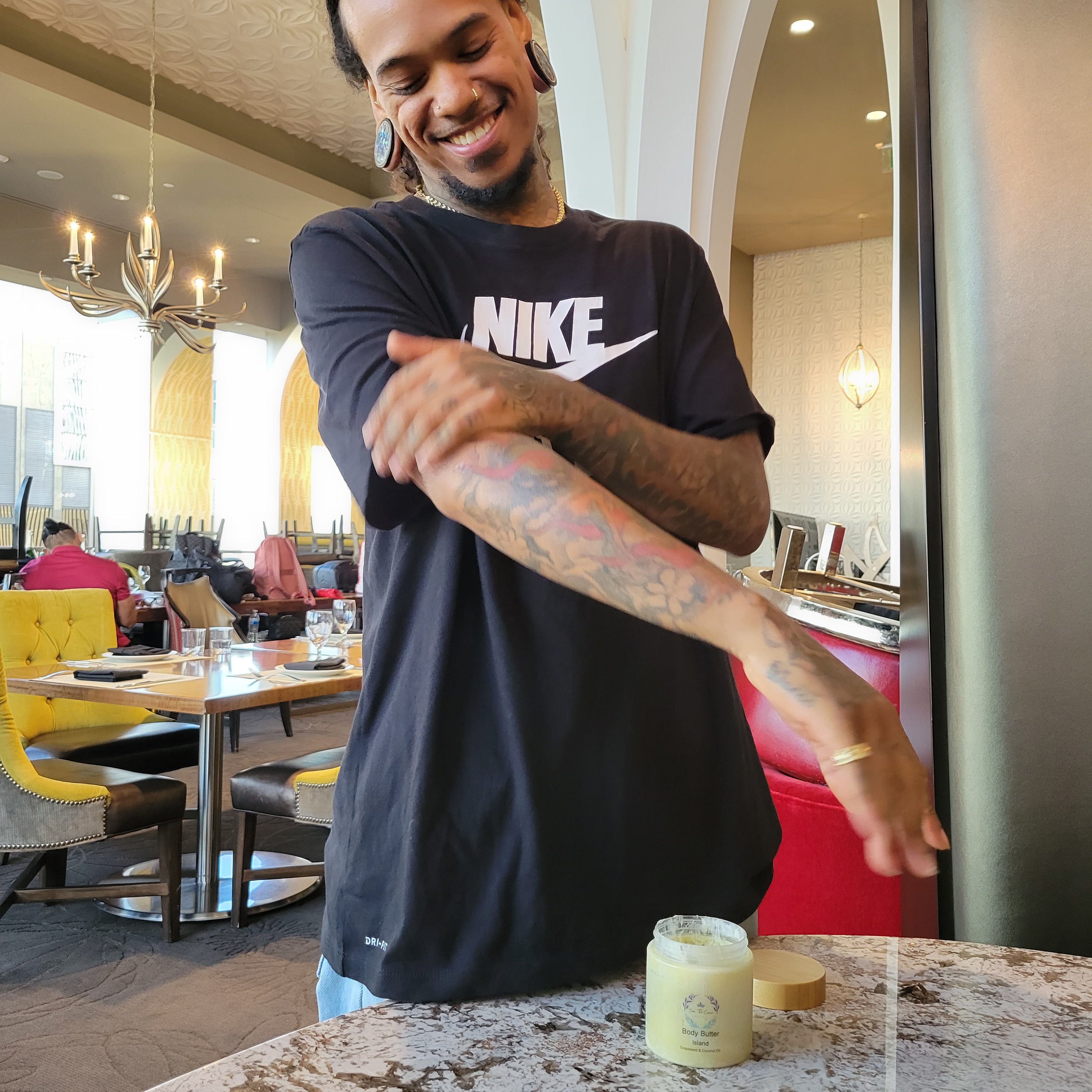 Deaf Dancer Shaheem applying Sea The Crown butter to his tattoos